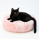 gato deitado sobre cama redonda de pelucia cor salmão